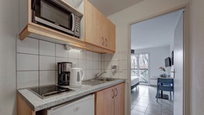 A compact kitchen with a microwave, coffee maker, and sink. - Comfort Aparthotel Divonne L'Oree du Parc (Divonne-les-Bains)