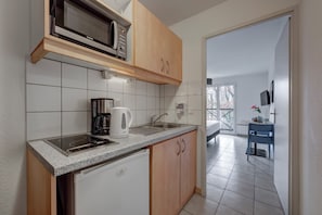 Cocina pequeña con microondas, cafetera y lavabo.