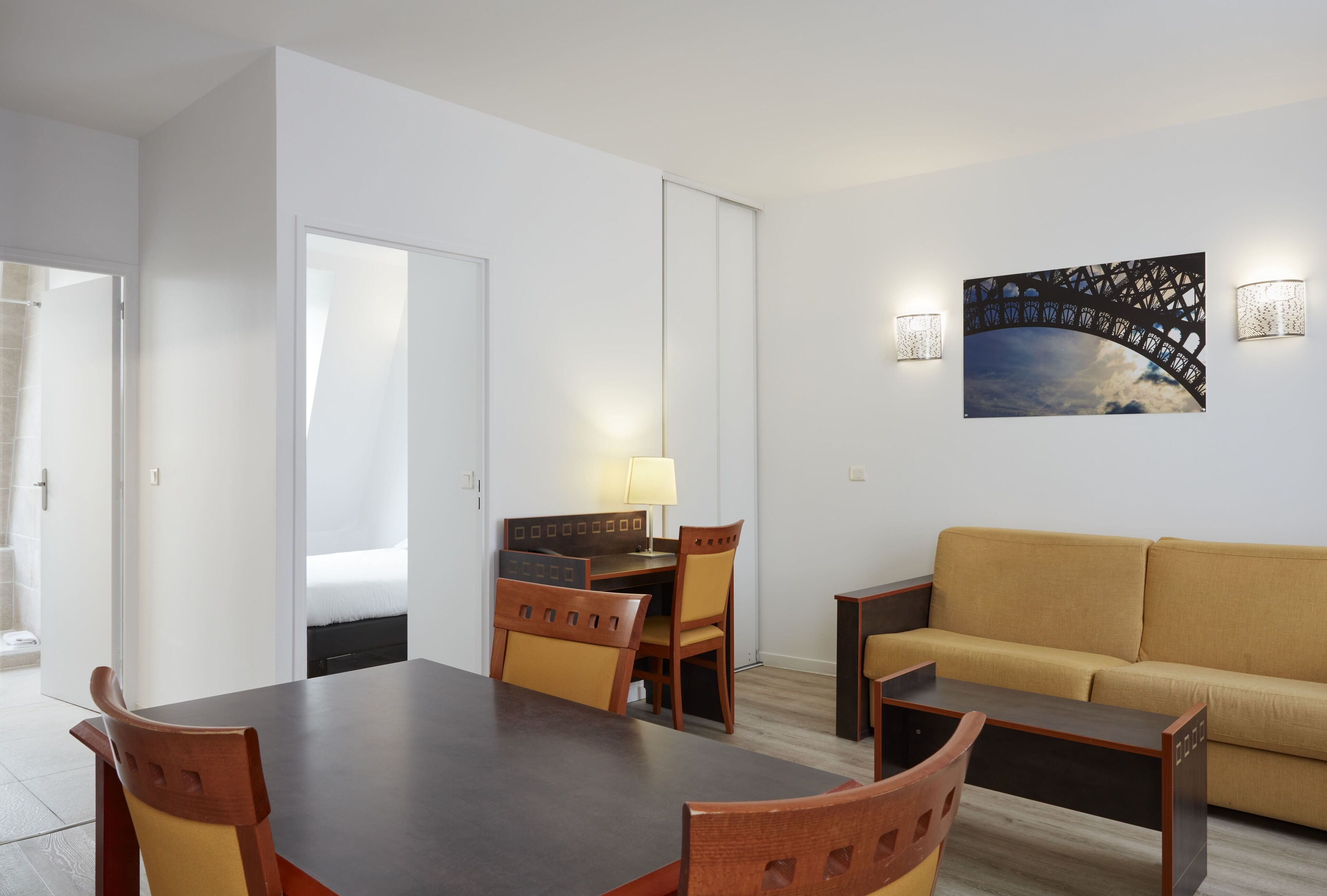 Una habitación de hotel moderna con una mesa de comedor, sillas, un sofá y un cuadro en la pared.