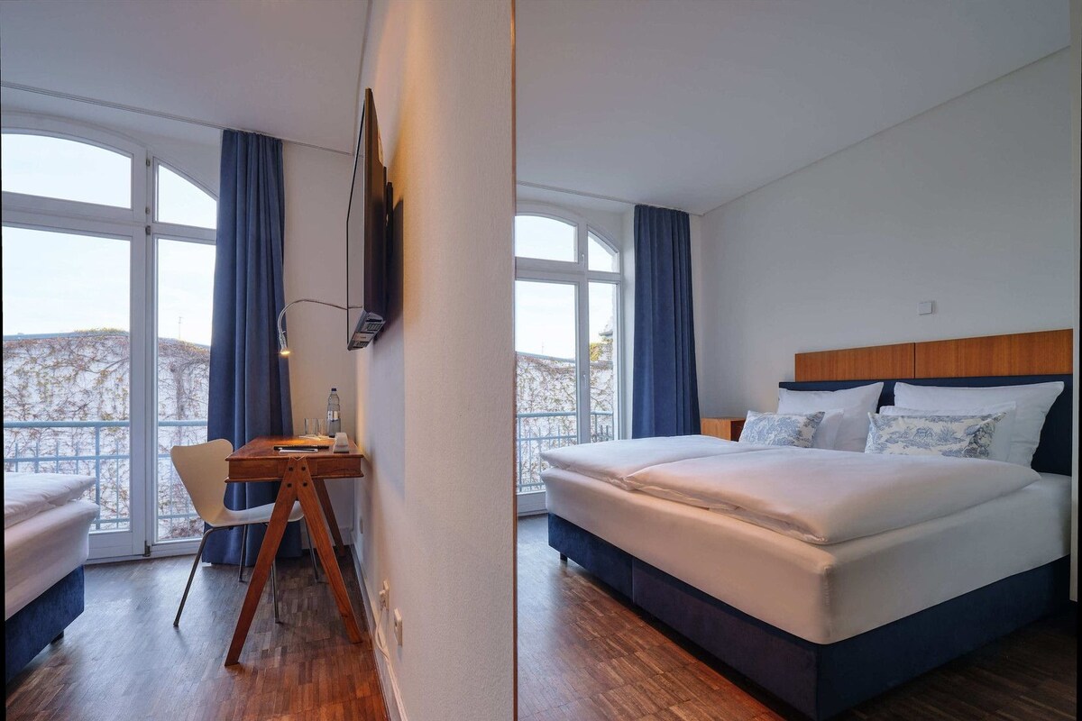 A hotel room with a bed, a desk, and a chair.
