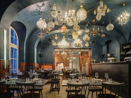 Ein Restaurant mit mehreren Tischen und Stühlen, einer Bar und verschiedenen Kronleuchtern.