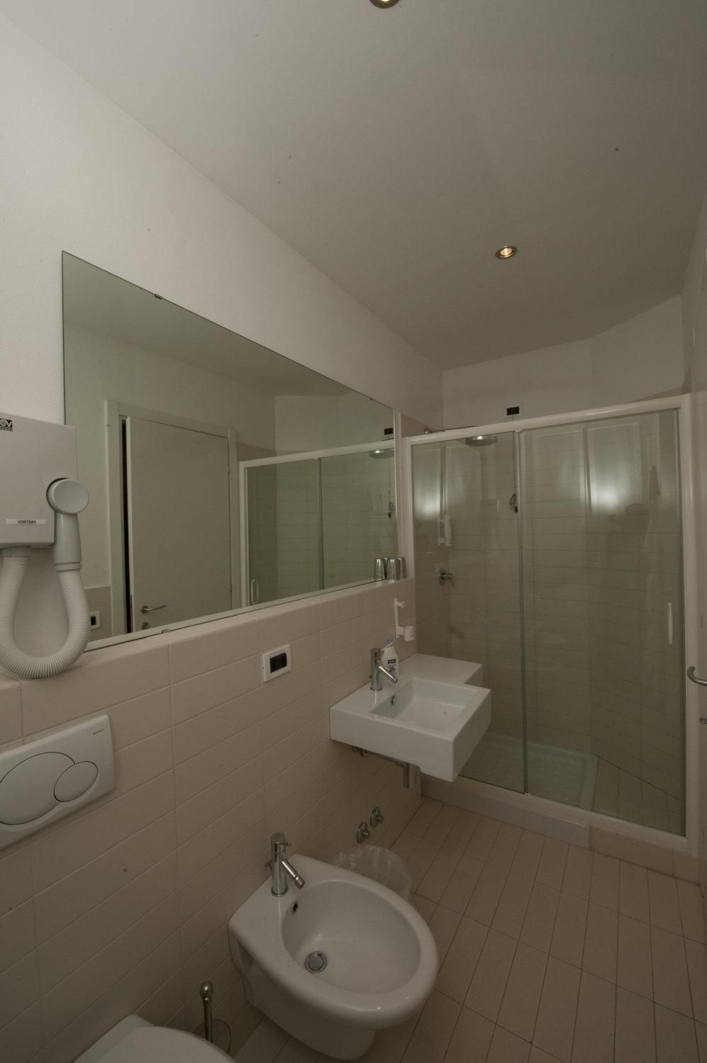 A modern bathroom with a glass-enclosed shower, a bidet, and a sink.