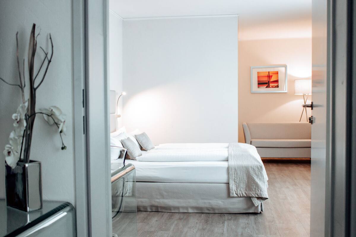 Ein modernes Schlafzimmer mit zwei Betten, einem Nachttisch, einer Lampe und einem gerahmten Bild an der Wand.