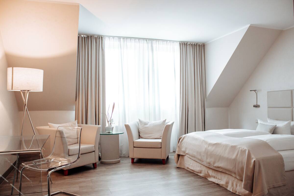 Ein modernes Hotelzimmer mit einem Bett, einem Sessel, einem kleinen Tisch und einer Lampe.