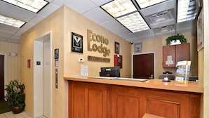 A reception desk with a wooden counter, a sign reading "Econo Lodge by Choice Hotels," and a potted plant to the left. - Econo Lodge Valdosta Mall Area (Valdosta)