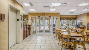 A hotel lobby with a reception desk, a glass door entrance, and a dining area with tables and chairs. - Econo Lodge Valdosta Mall Area (Valdosta)