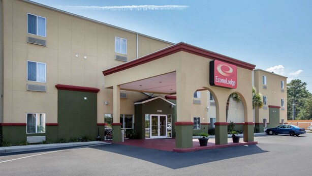 A hotel with a red and beige facade, a covered entrance, and a parking lot. - Econo Lodge Valdosta Mall Area (Valdosta)