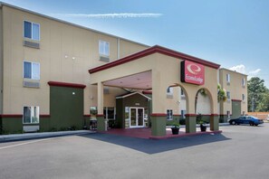 A hotel with a red and beige facade, a covered entrance, and a parking lot. - Econo Lodge Valdosta Mall Area (Valdosta)