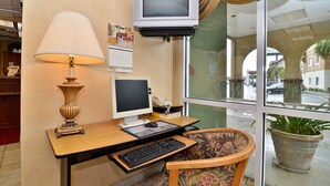 A desk with a computer, a lamp, and a chair in a room with a window. - Econo Lodge Valdosta Mall Area (Valdosta)