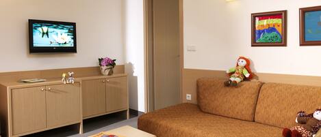 A hotel room with a wooden cabinet, a television, a sofa, and a small table.