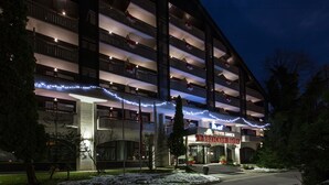 Un hotel de varios pisos con balcones, una entrada central y luces decorativas.