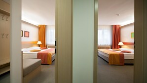 Habitación de hotel con dos camas, un armario, un escritorio y una ventana con cortinas.