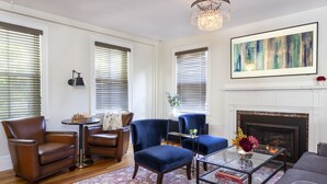 A living room with a fireplace, a chandelier, and a large abstract painting. - Chapter House (Yarmouth Port)