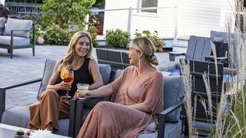 Two people seated on outdoor patio furniture, holding drinks.