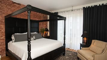 Un lit à baldaquin dans une pièce avec un mur en briques, un rideau noir et un tapis à motifs.