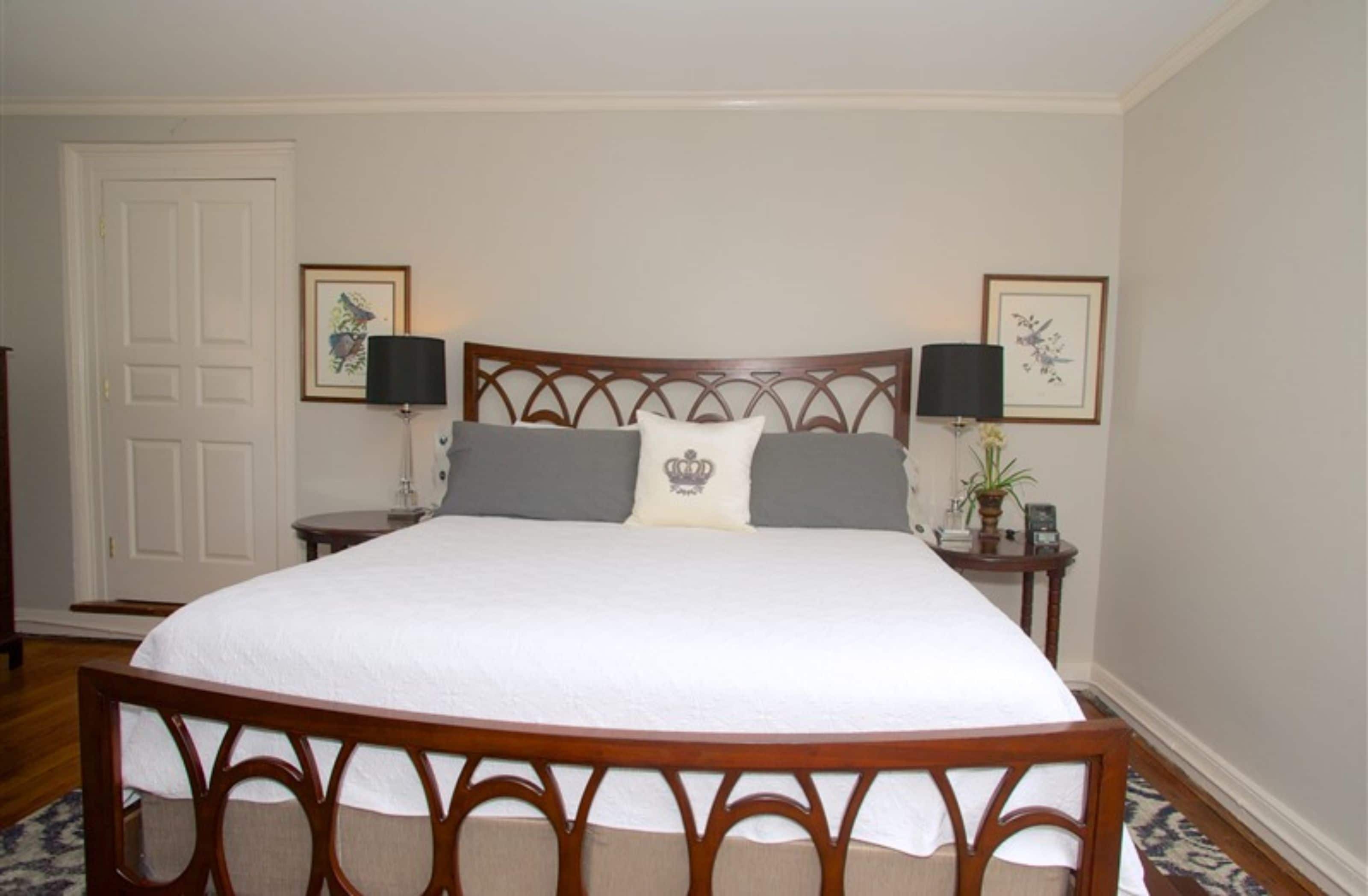 A neatly made bed with a wooden headboard, two bedside tables with lamps, and framed artwork on the walls.