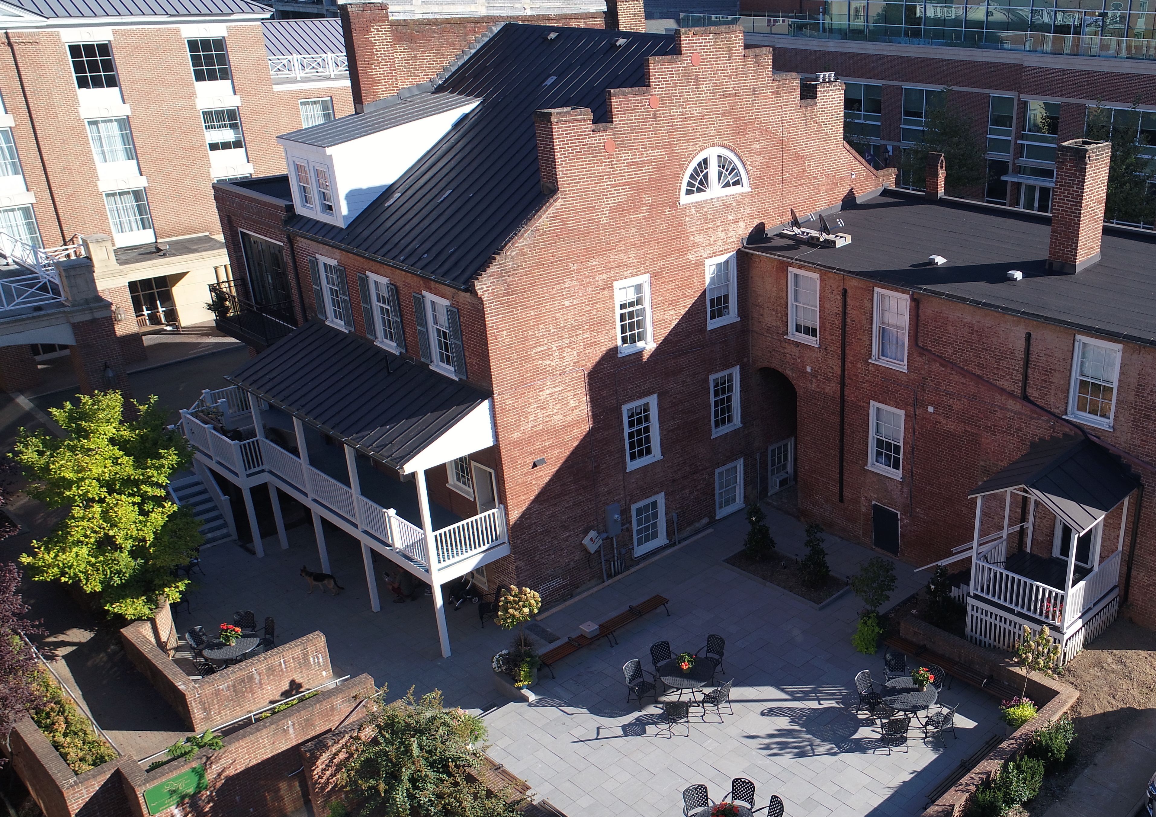 A multi-story brick building with a courtyard featuring outdoor seating and a small garden.