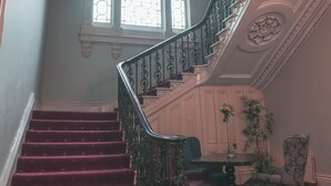 A grand staircase with ornate railings and a chandelier, leading to a room with a large window and a floral arrangement. - Boyne Valley Hotel - Bed & Breakfast Only (Drogheda)