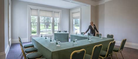 Una sala de conferencias con una mesa grande, sillas y una persona organizando objetos.