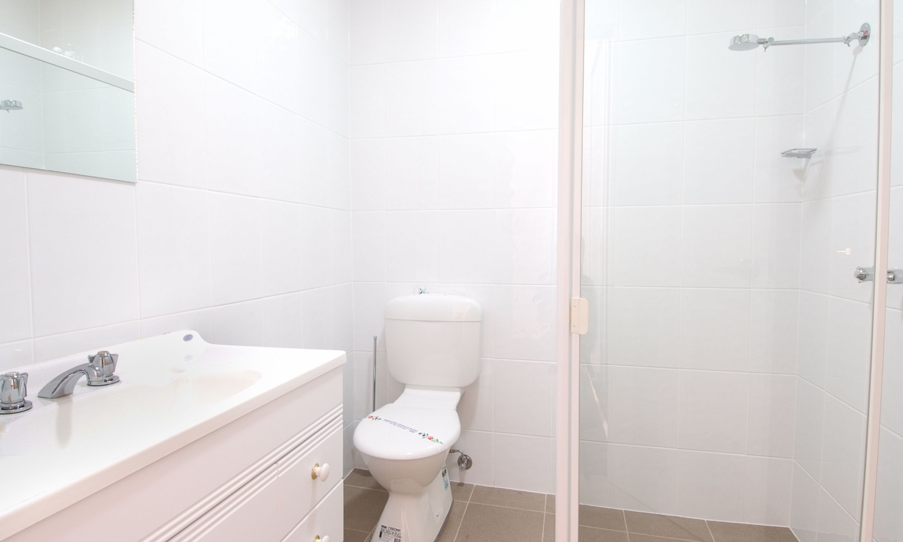 A bathroom with a white sink, a toilet, and a shower area.