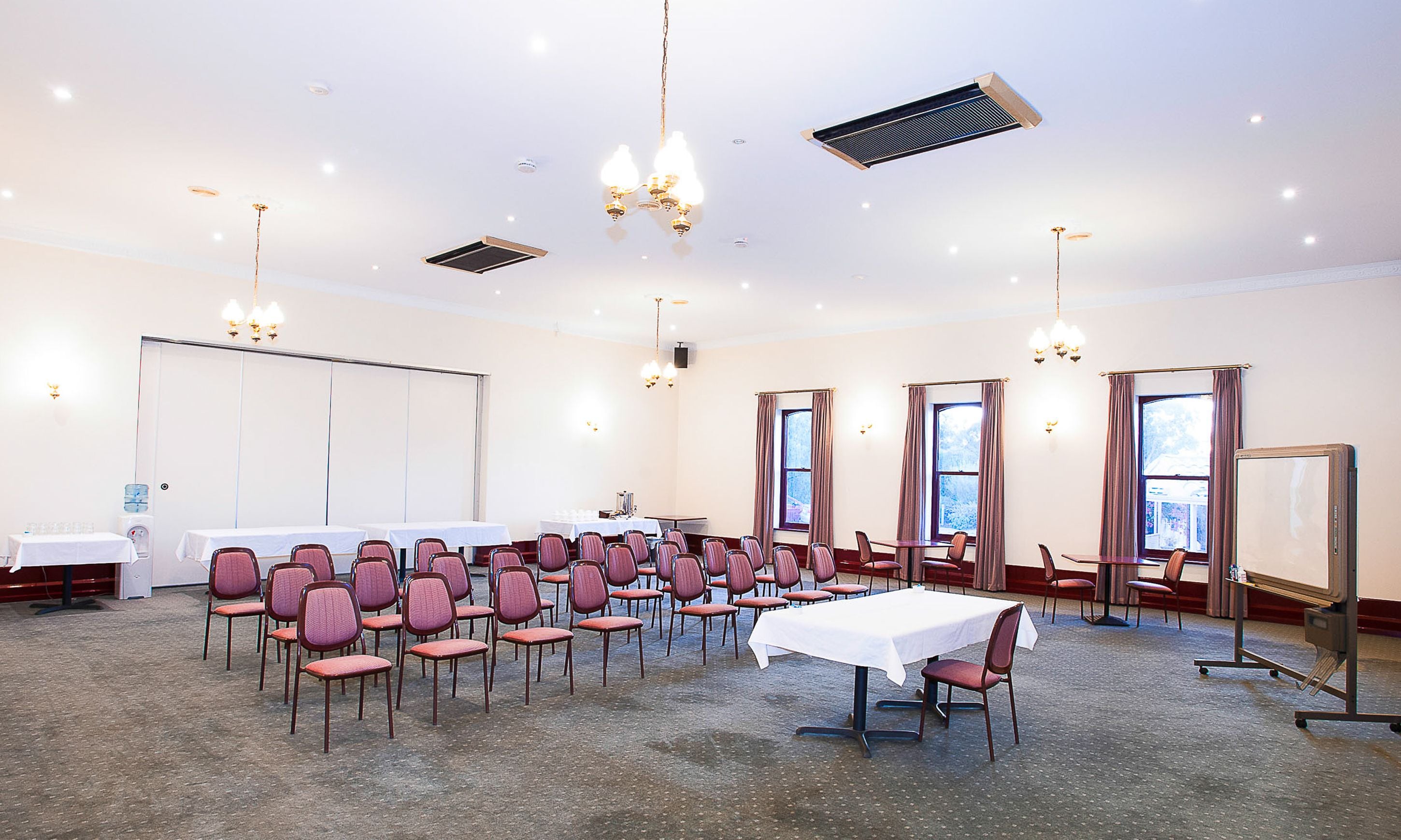 A conference room with rows of chairs, a large table, and a projector screen.