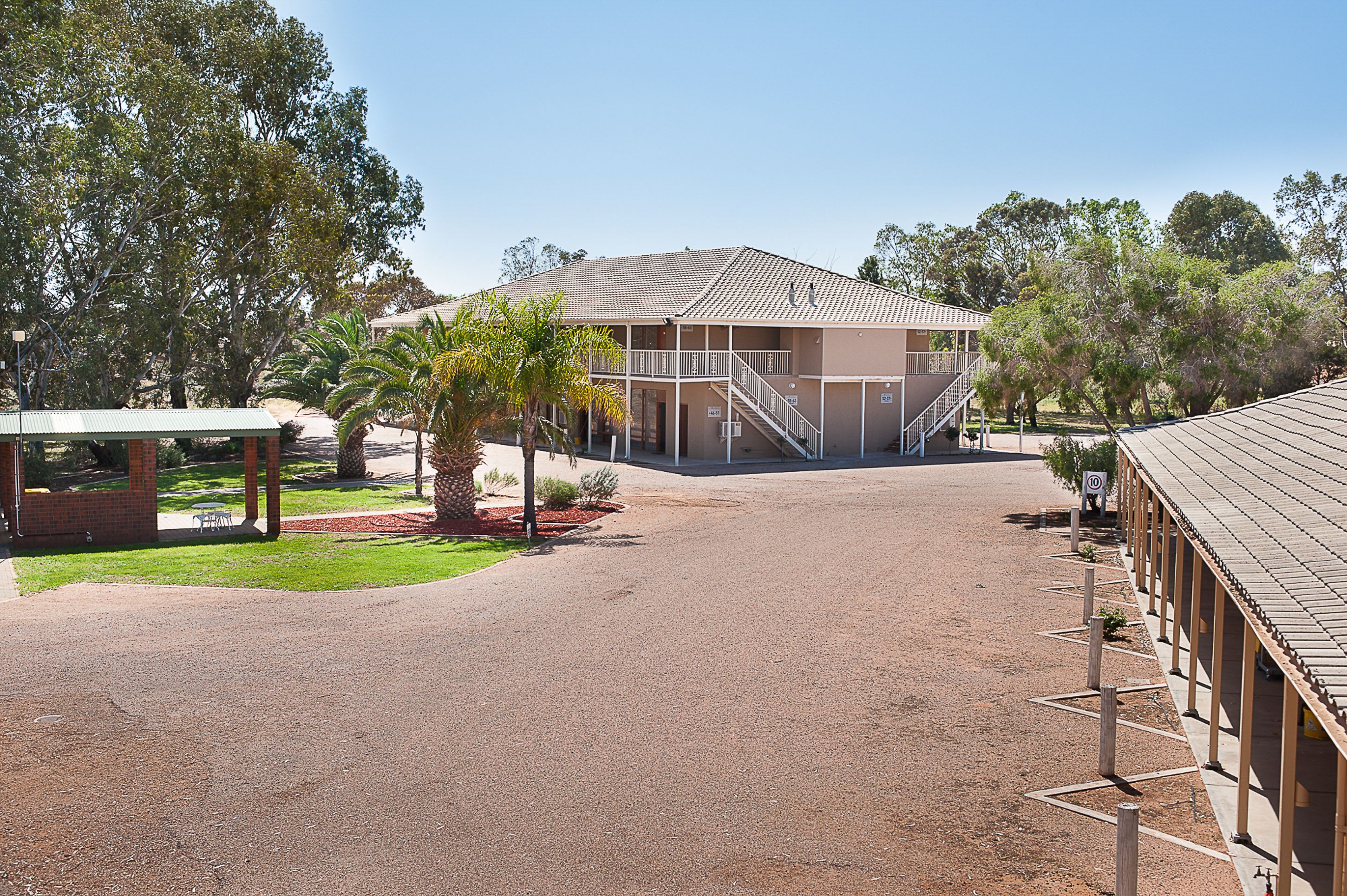 A building with a covered walkway and a staircase leading to a second floor.