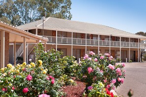 A motel with a two-story structure, a covered walkway, and a landscaped garden with roses. - The Standpipe Golf Motor Inn (Port Augusta West)