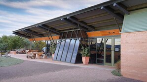 Un bâtiment doté d’une entrée couverte, de grandes fenêtres et d’un espace extérieur aménagé avec des plantes en pot.