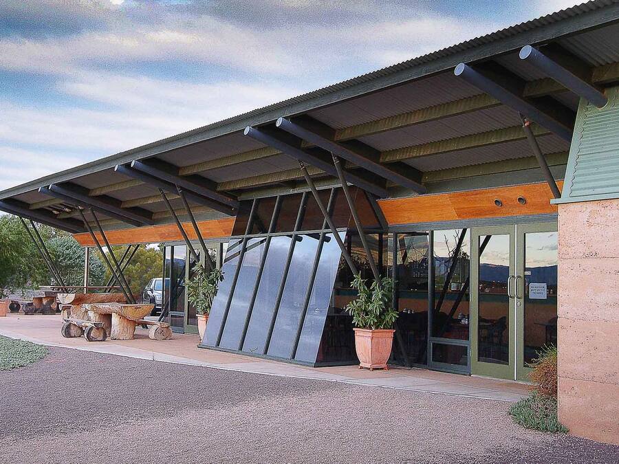 Un bâtiment doté d’une entrée couverte, de grandes fenêtres et d’un espace extérieur aménagé avec des plantes en pot.