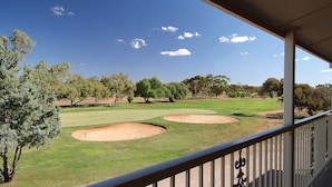 Un parcours de golf avec deux bunkers de sable, des arbres et un ciel bleu dégagé.