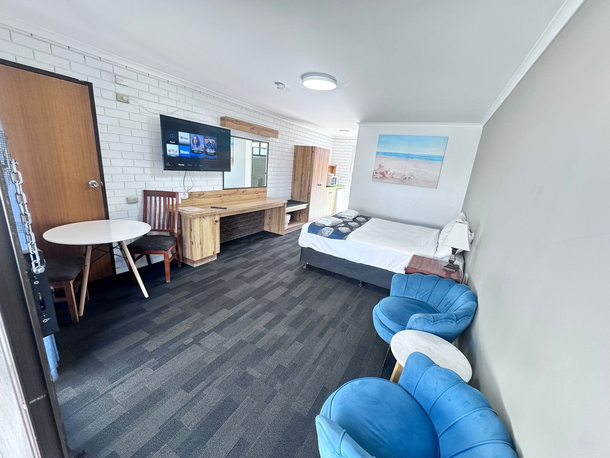 Una habitación de hotel moderna con cama, escritorio, televisor y zona de estar.