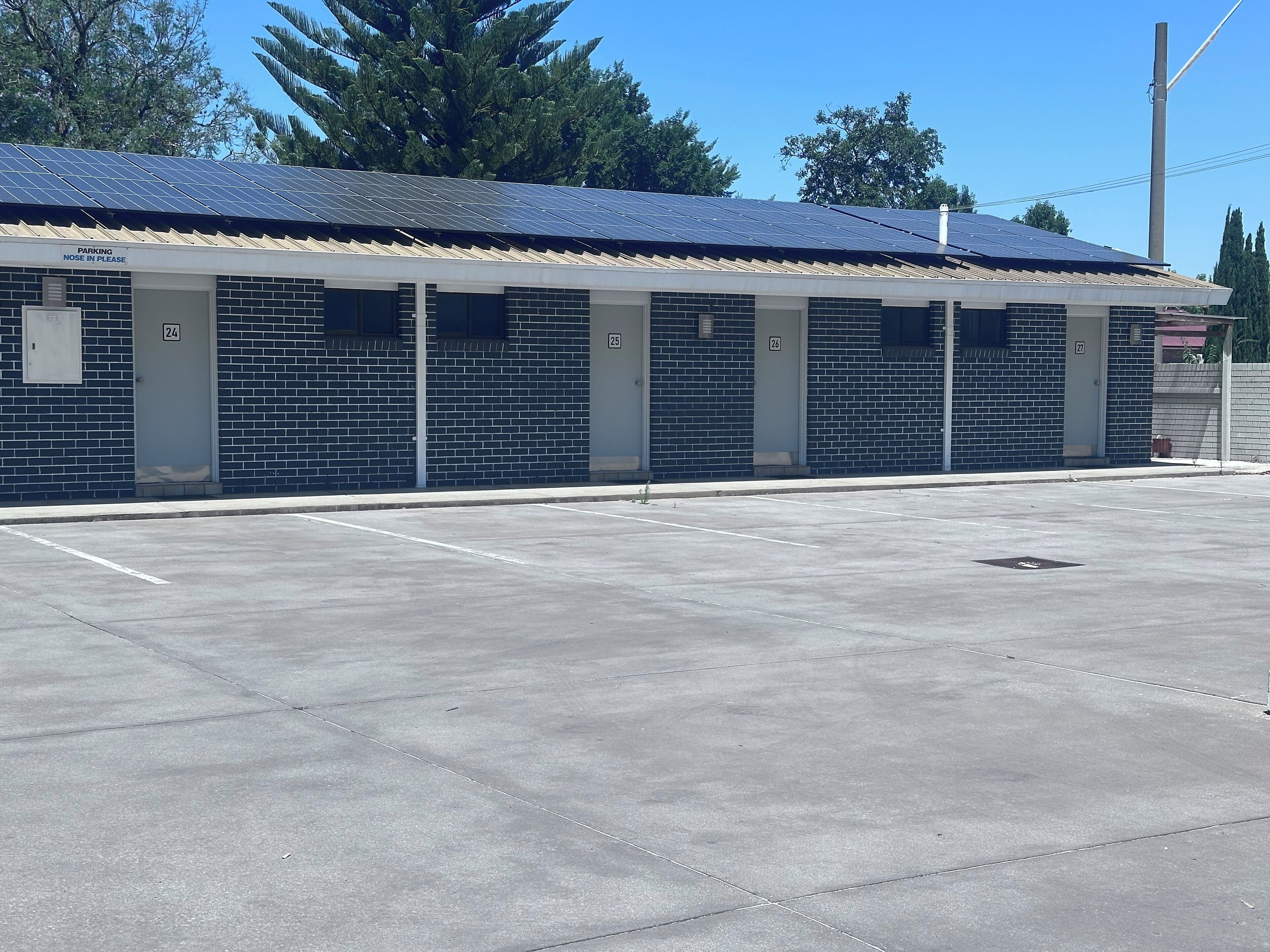 A building with a brick facade, numbered parking spaces, and a solar panel roof.