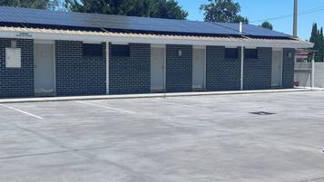 A building with a brick facade, numbered parking spaces, and a solar panel roof.