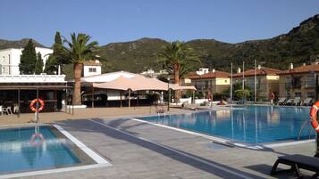 Una piscina al aire libre, sillones reclinables de piscina