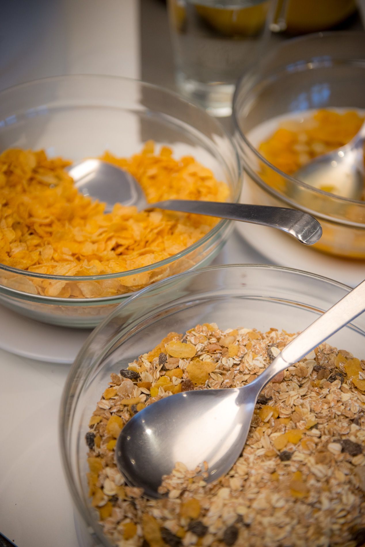 Three bowls of cereal with spoons.