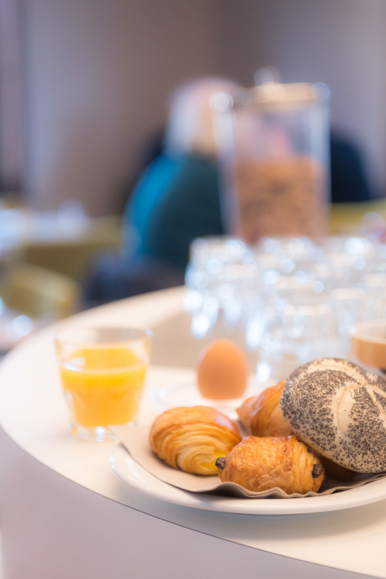A breakfast tray with croissants, a glass of orange juice, and a glass of milk.