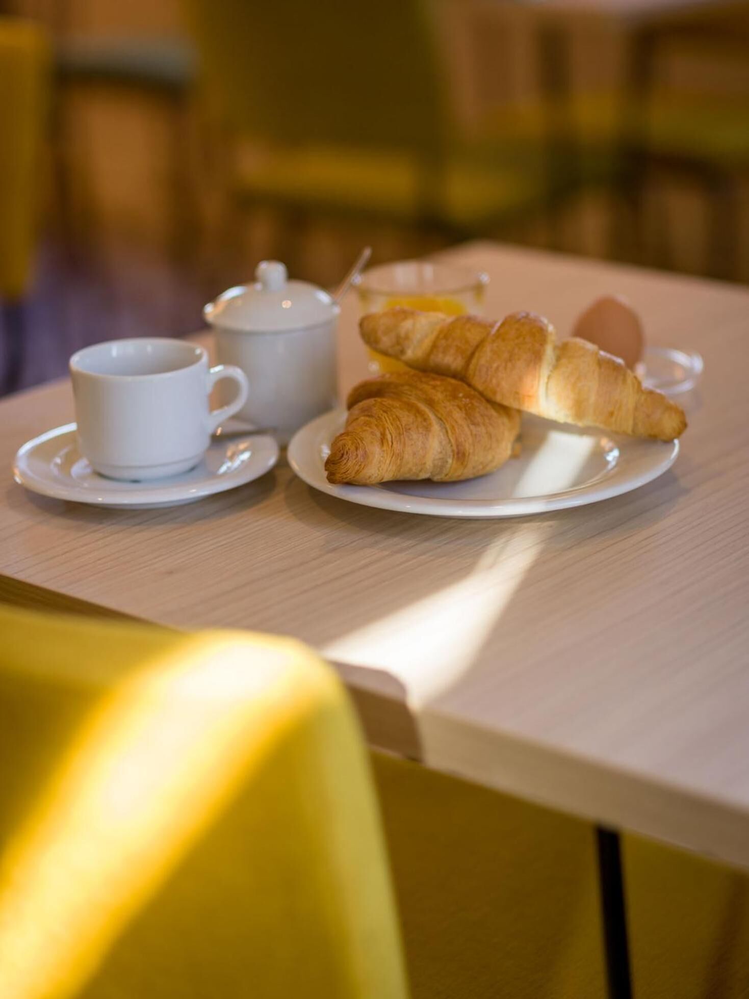 Une table mise pour le petit-déjeuner, avec des croissants, une tasse et une théière.