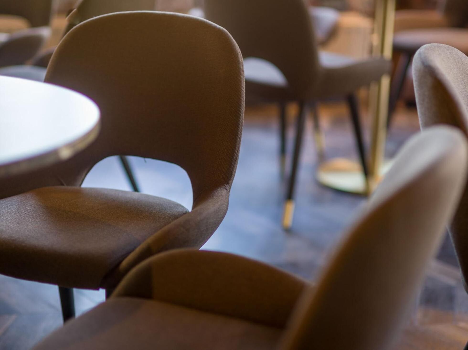 Gros plan d’une chaise avec un dossier incurvé et d’une table ronde dans un café.