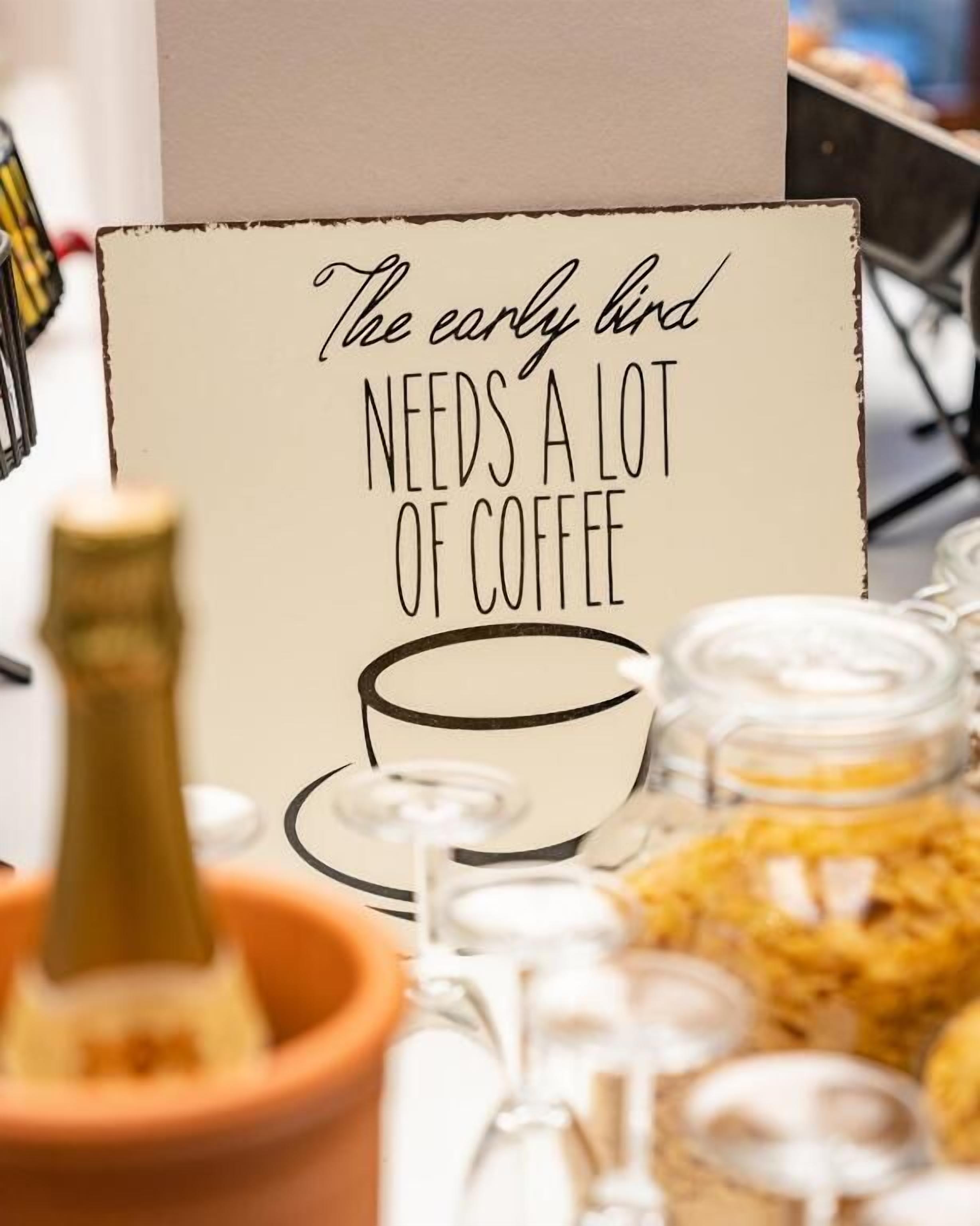 Um sinal com ilustração de uma xícara de café e o texto 'Quem madruga precisa de muito café'.