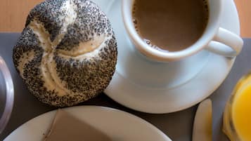 A breakfast setting with croissants, a poppy seed roll, and a cup of coffee on a table.