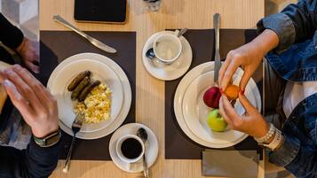 A table with plates of food, a cup of coffee, and a smartphone.