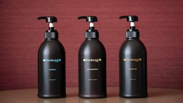 Three black bottles of Ella Baché Paris products: shampoo, hair treatment, and shower gel.