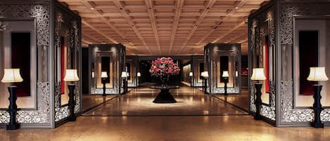 A long, elegant hallway with ornate wall panels and a central floral arrangement.