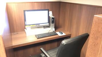 A cubicle with a desktop computer, keyboard, mouse, and a black office chair.