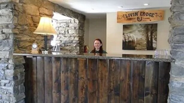 Un mostrador de recepción con un fondo de pared de piedra y un letrero que dice "LIVIN' LODGE".