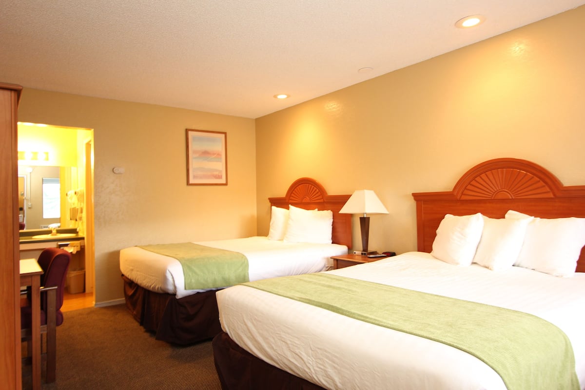 A hotel room with two beds, a desk, and a chair.