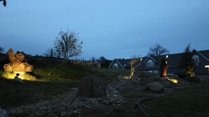 Una zona residencial con casas, un sendero y una roca grande al frente.