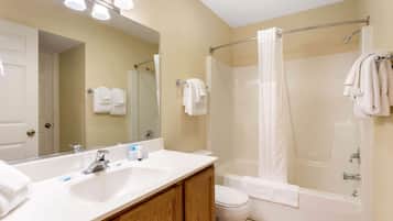 Un baño con lavamanos, espejo, inodoro y bañera.