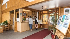 A wooden interior with a reception desk, potted plants, and informational posters. - Odalys Résidence Les Chalets d'Evian (Evian-les-Bains)