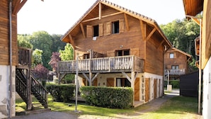 A wooden chalet with a balcony, a staircase, and a garden area. - Odalys Résidence Les Chalets d'Evian (Evian-les-Bains)
